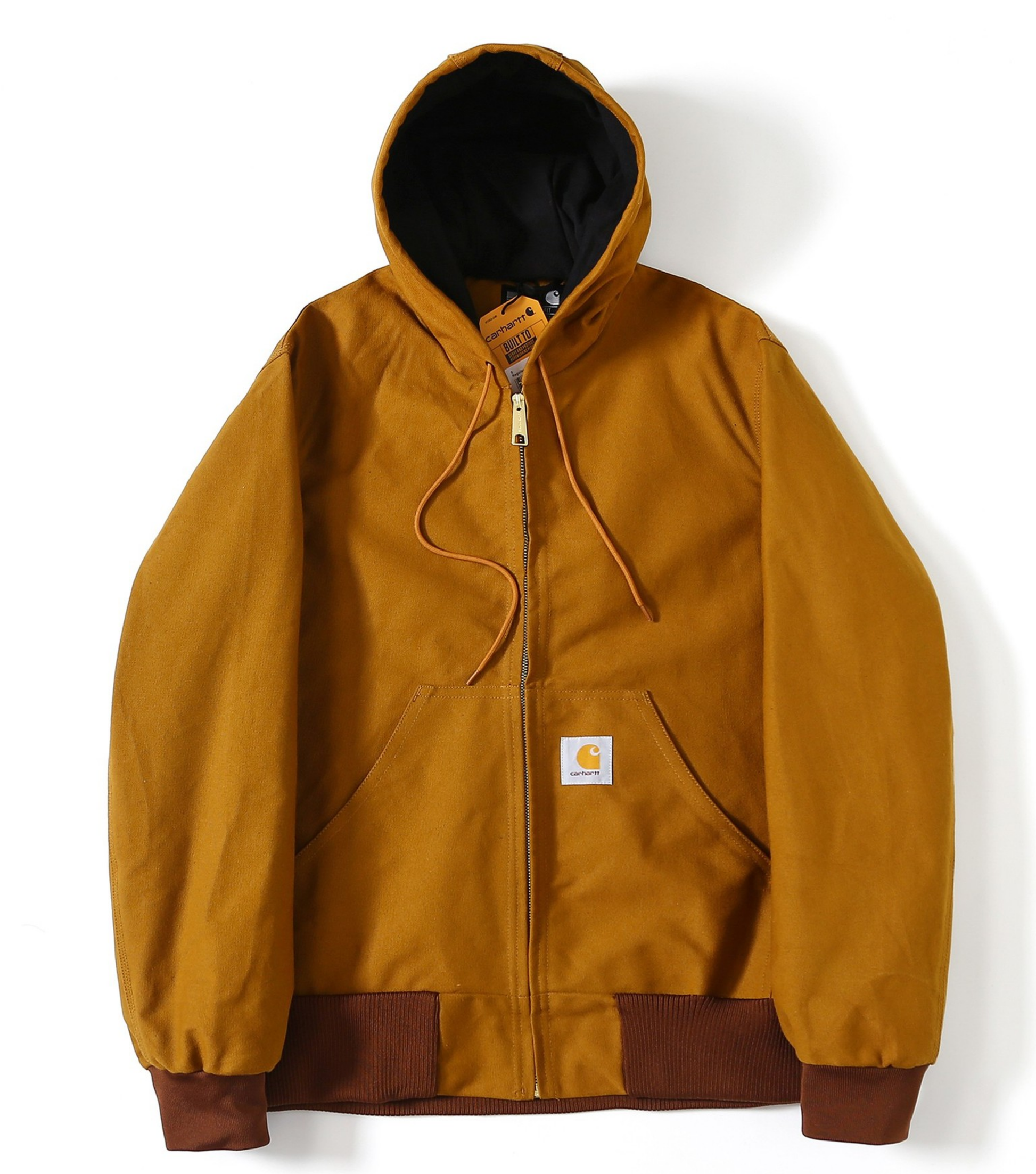 A Carhartt J140 hooded jacket in a warm camel-brown color, featuring a black-lined hood, a front zipper, drawstrings, a kangaroo pocket, and ribbed cuffs and hem. The Carhartt brand logo patch is visible on the chest.