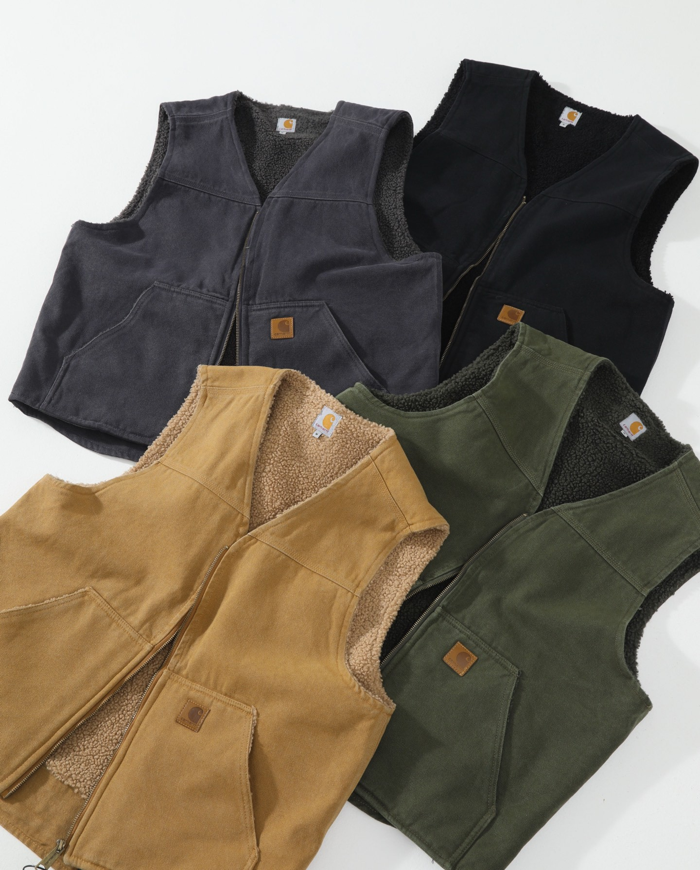 Four Carhartt vest jackets in different colors (charcoal, black, tan, and olive green) arranged in a flat-lay pattern on a white background.