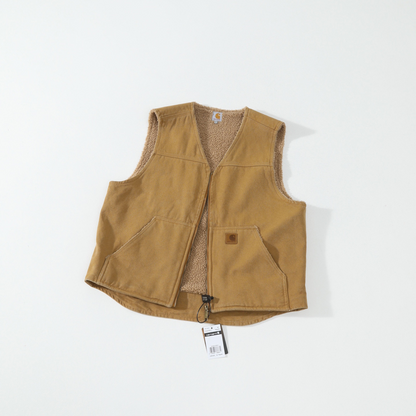 A tan corduroy carhartt vest with a brown sherpa lining, laid flat on a white background. It features a small brown leather patch on the front pocket