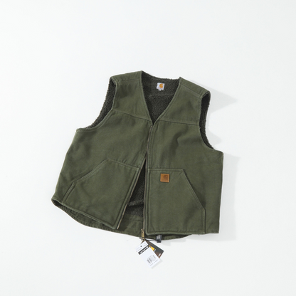 An olive green Carhartt vest with a black sherpa lining, laid flat on a white background with a small leather logo patch and hangtag visible.